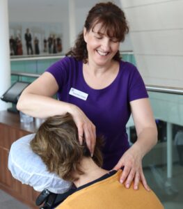 Person receiving neck massage whilst relaxing in the special ergonomic on site massage chair at an event